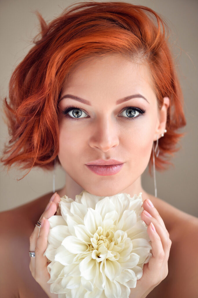 Πορτρέτο νεαρής όμορφης κοκκινομάλλας γυναίκας με λευκό λουλούδι