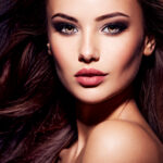 Όμορφη καστανή γυναίκα με μακριά μαλλιά και προσεγμένο μακιγιάζ