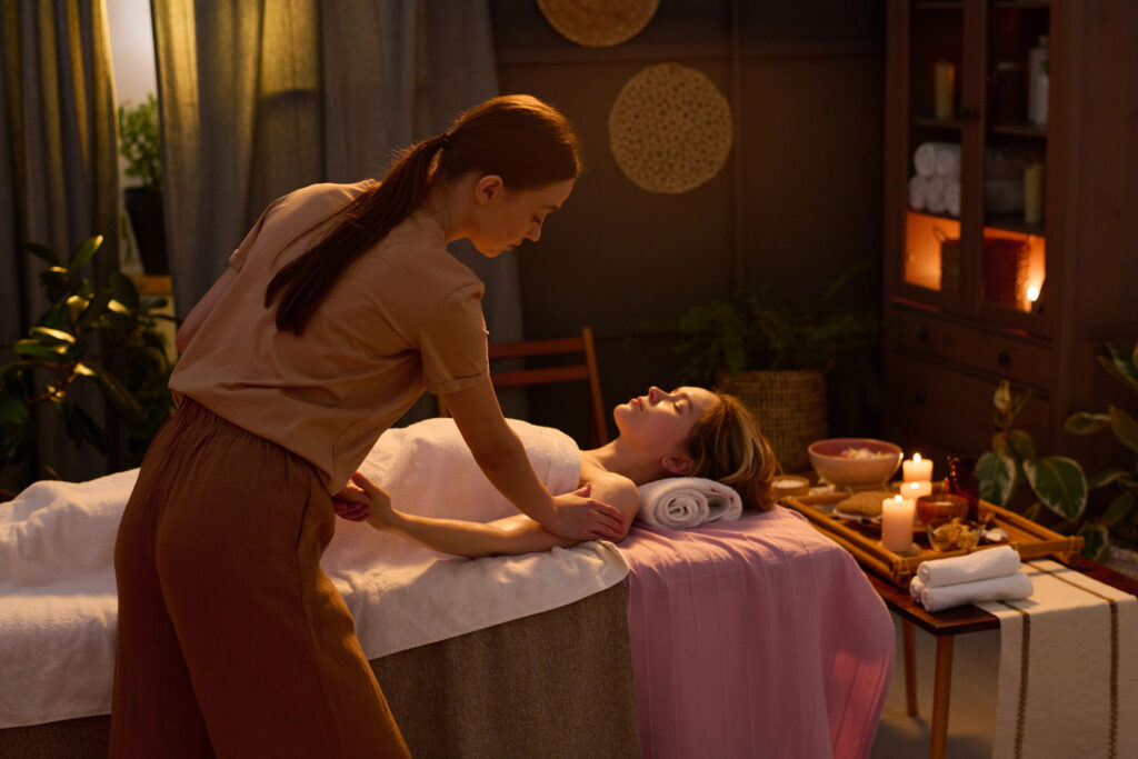 ξανθιά γυναίκα με μαλακή πετσέτα ξαπλωμένη και απολαμβάνοντας βαθύ ολιστικό μασάζ με από μασέρ