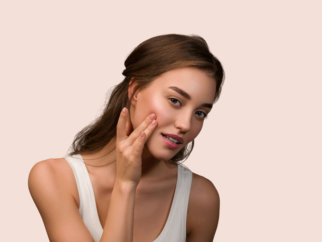 Ομορφη καστανή γυναίκα ακουμπαέι το χέρι της στο καθαρό υγιές πρόσωπό της
