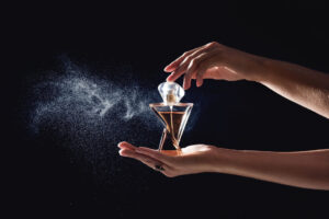 νεαρή γυναίκα ψεκάζει άρωμα σε μαύρο φόντο